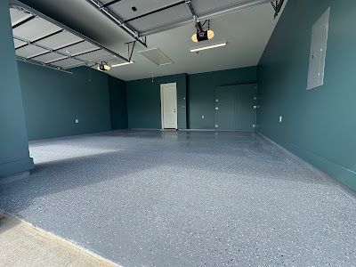 An empty garage with a gray floor and green walls.