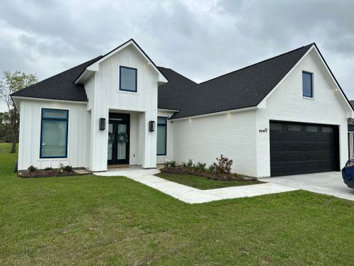 A white house with a black roof and a black garage door.