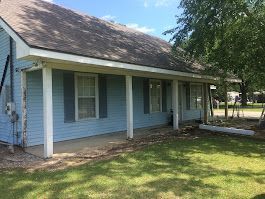 A blue house with a porch and shutters on it.