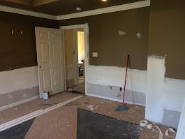 A room with brown walls and white trim is being painted.