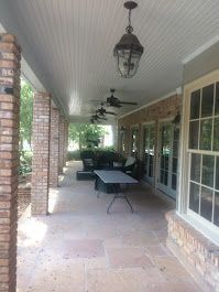 A large porch with a table , chairs and ceiling fans.