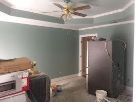 A room with a ceiling fan and a refrigerator in it.