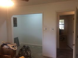 A living room with white walls and a ceiling fan.