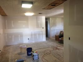 A room with white walls and a blue bucket on the floor.