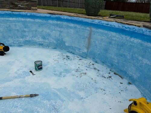 A swimming pool with a drill and a bucket of paint on the bottom.