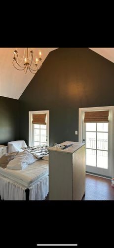 A bedroom with a bed , dresser , and two windows.