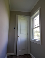 A hallway with a white door and a window.