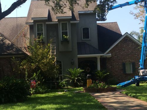 A large brick house with a blue crane in front of it.