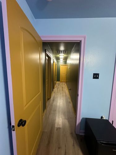 A hallway with a yellow door and a pink trim.