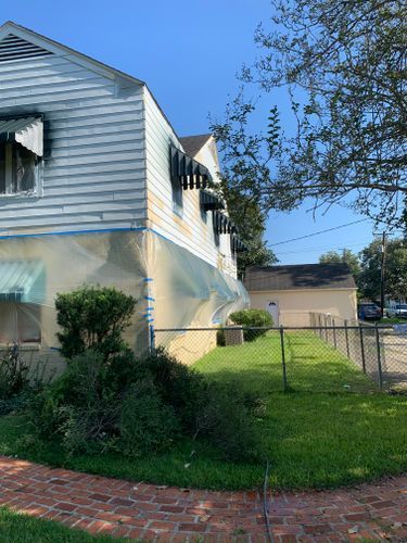 A house is covered in plastic while being painted.