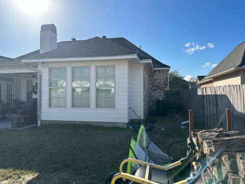 A house with a lot of windows and a fence in the backyard.