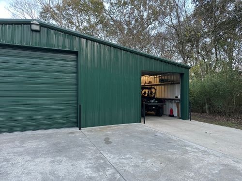 A green metal garage with a car parked inside of it.