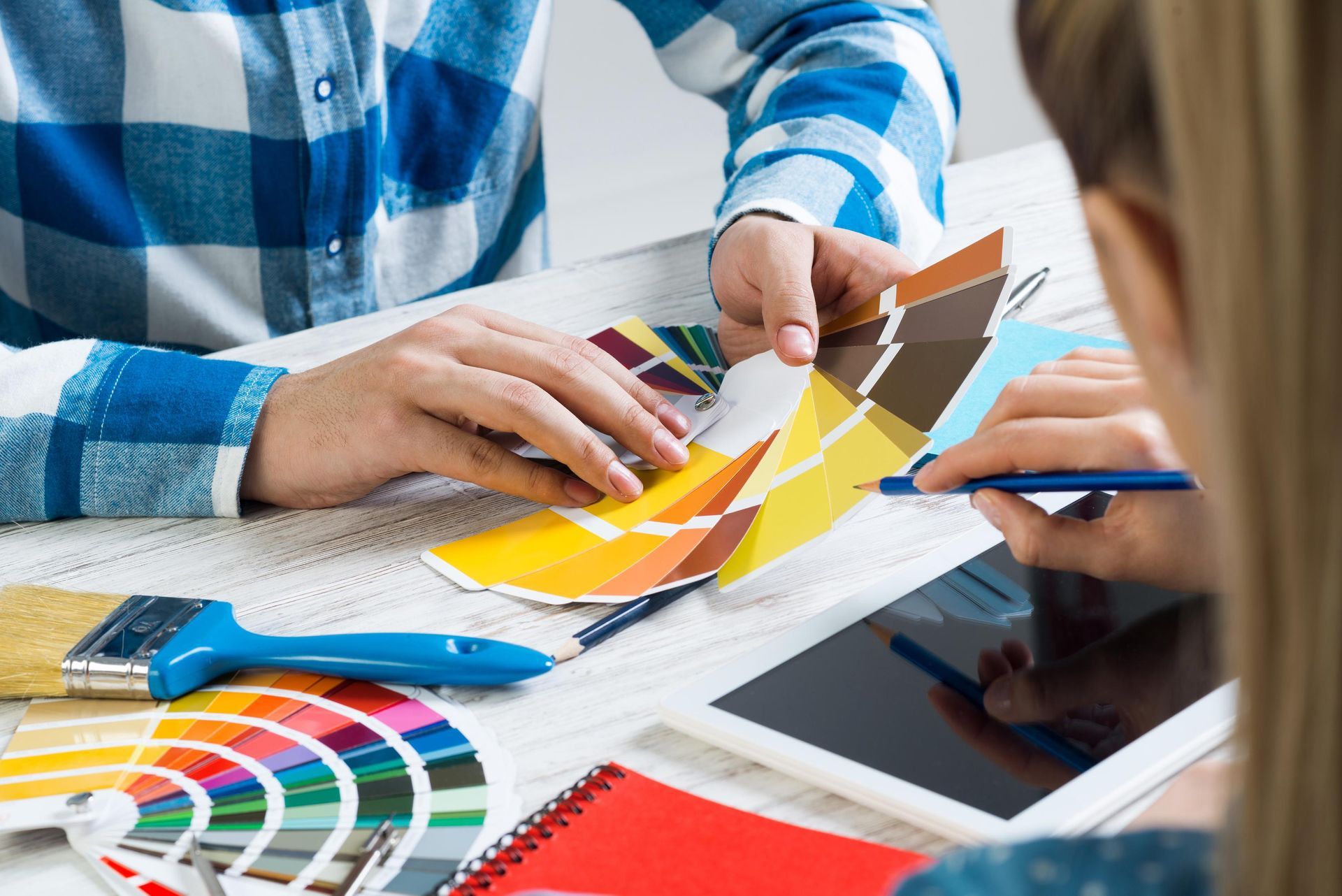 A man and a woman are sitting at a table looking at a color palette.