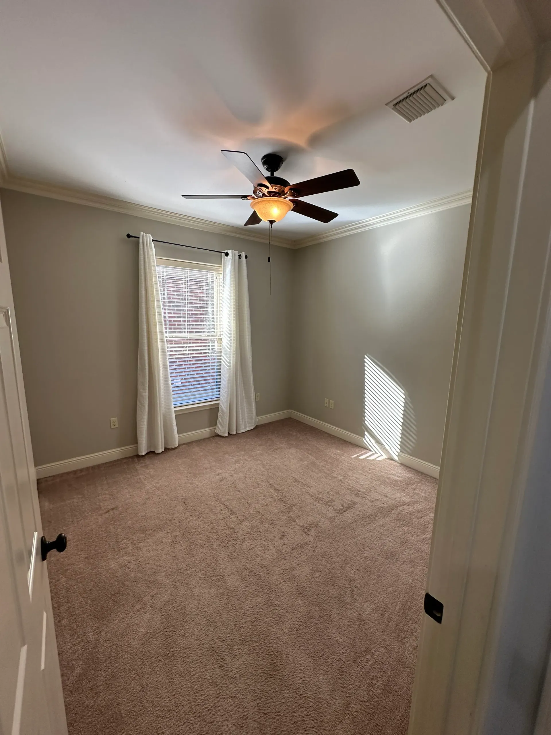 A bedroom with a ceiling fan and a window.