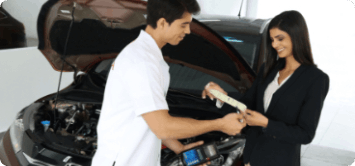 Um homem de terno está segurando um tablet na frente de um carro.