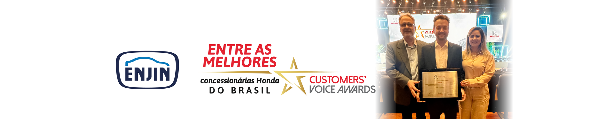 Lojas de um centro comercial com toldos vermelhos e carros estacionados sob um céu azul.