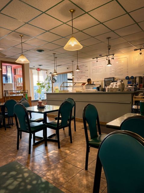 Empty café interior with green chairs, hanging lamps, and a counter in the background