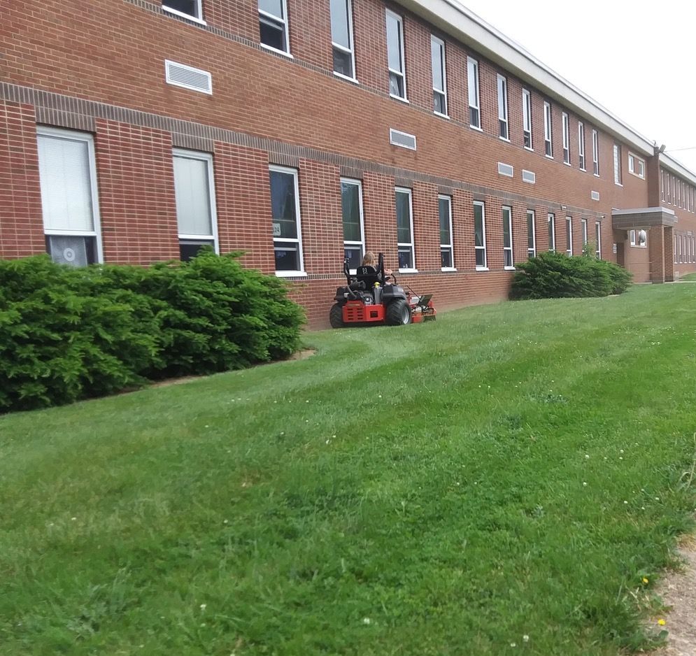 A person is riding a tractor through a grassy field.