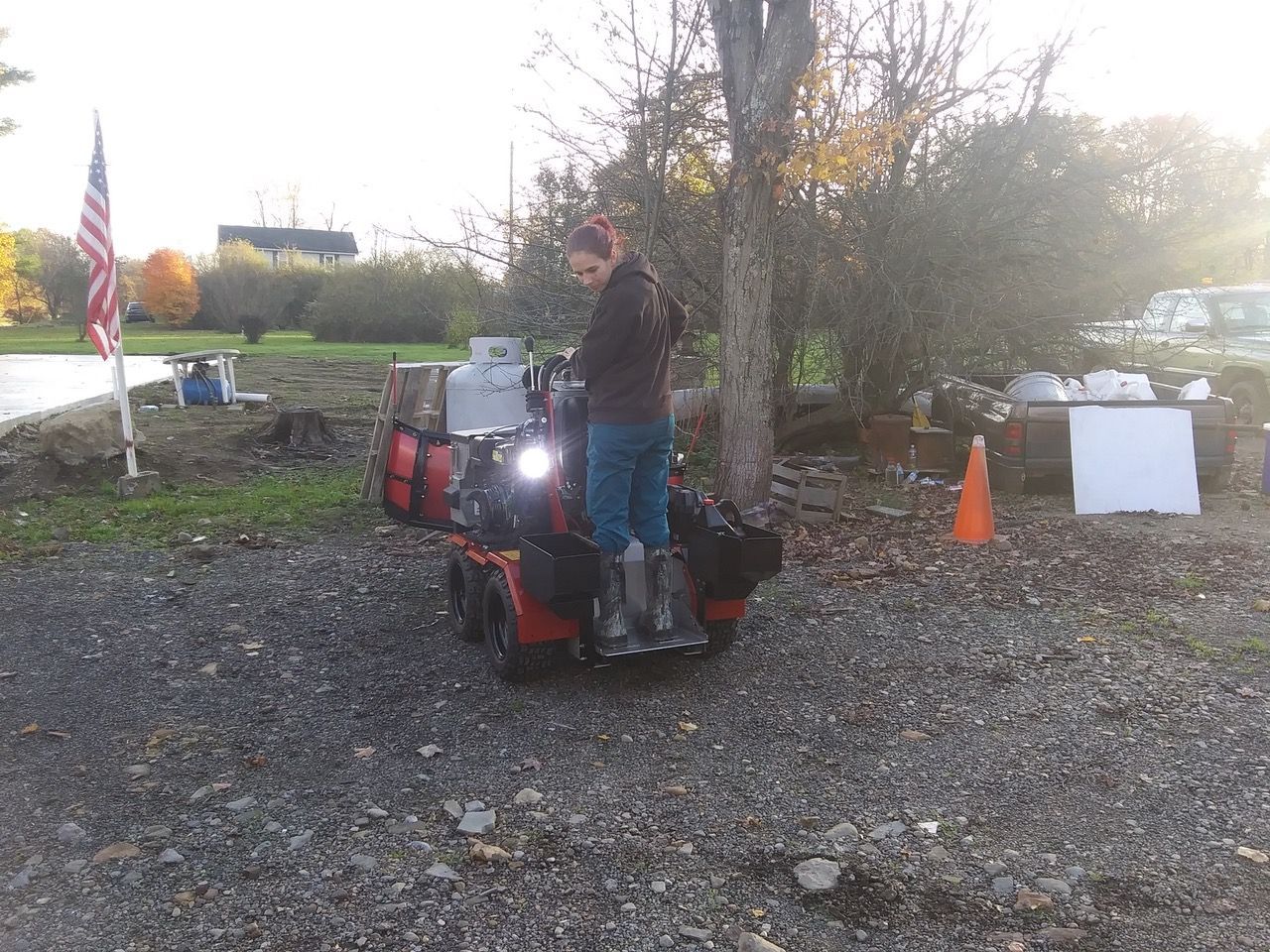 A woman standing next to a lawn mower in a parking lot