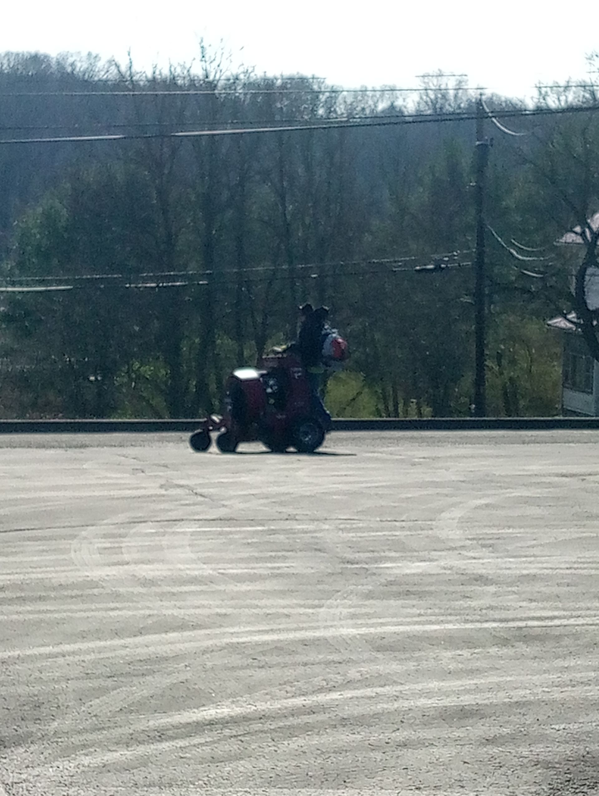 A person is riding on the back of a tractor in a parking lot