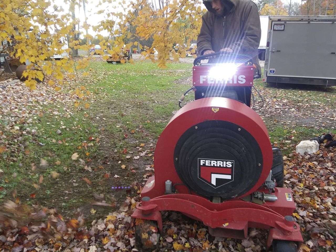 A ferris lawn blower is being used to blow leaves