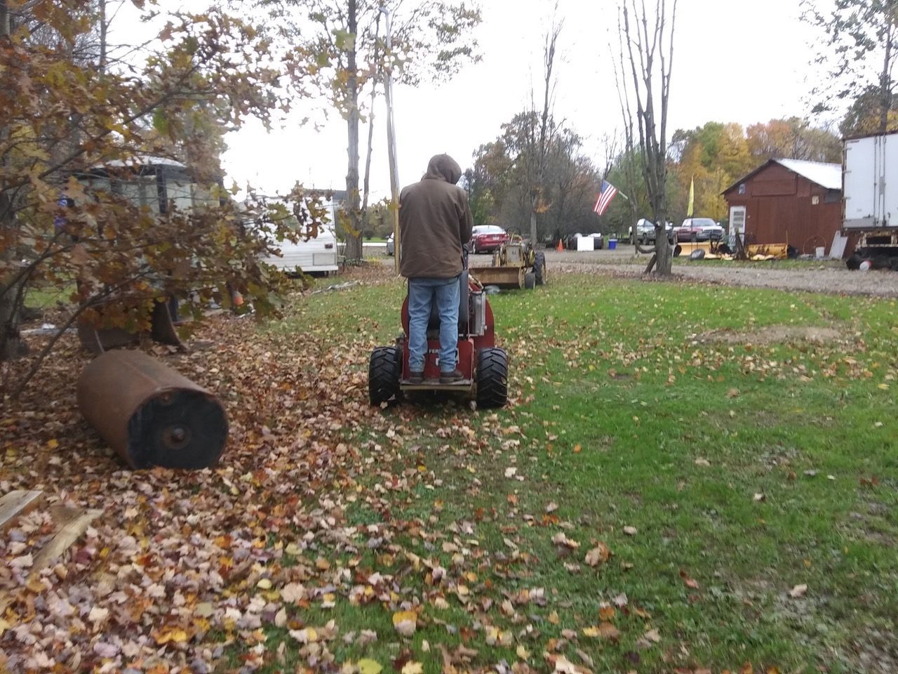 A man is riding a leaf blower through leaves.