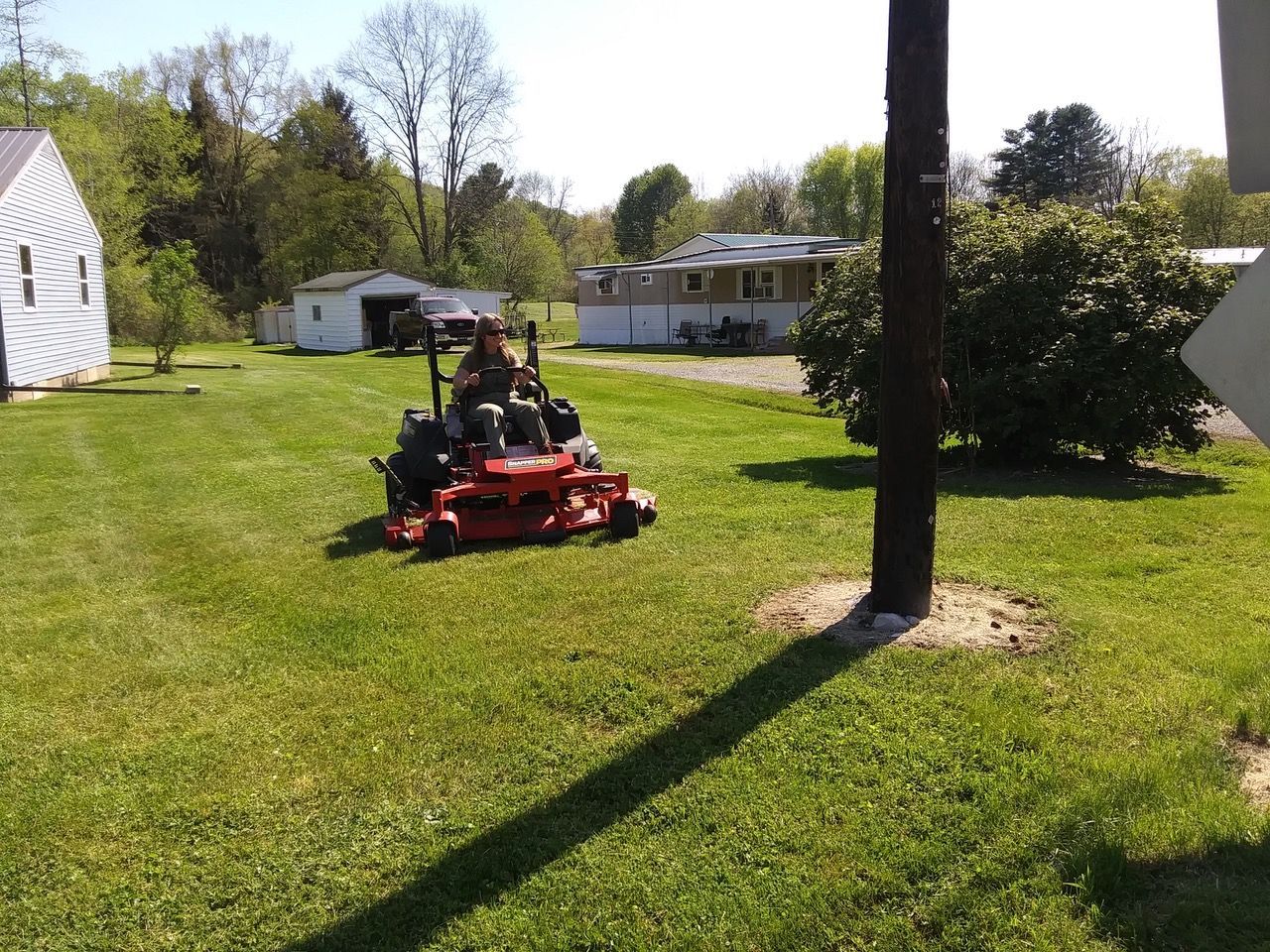 A person is riding a red lawn mower on a lush green lawn.
