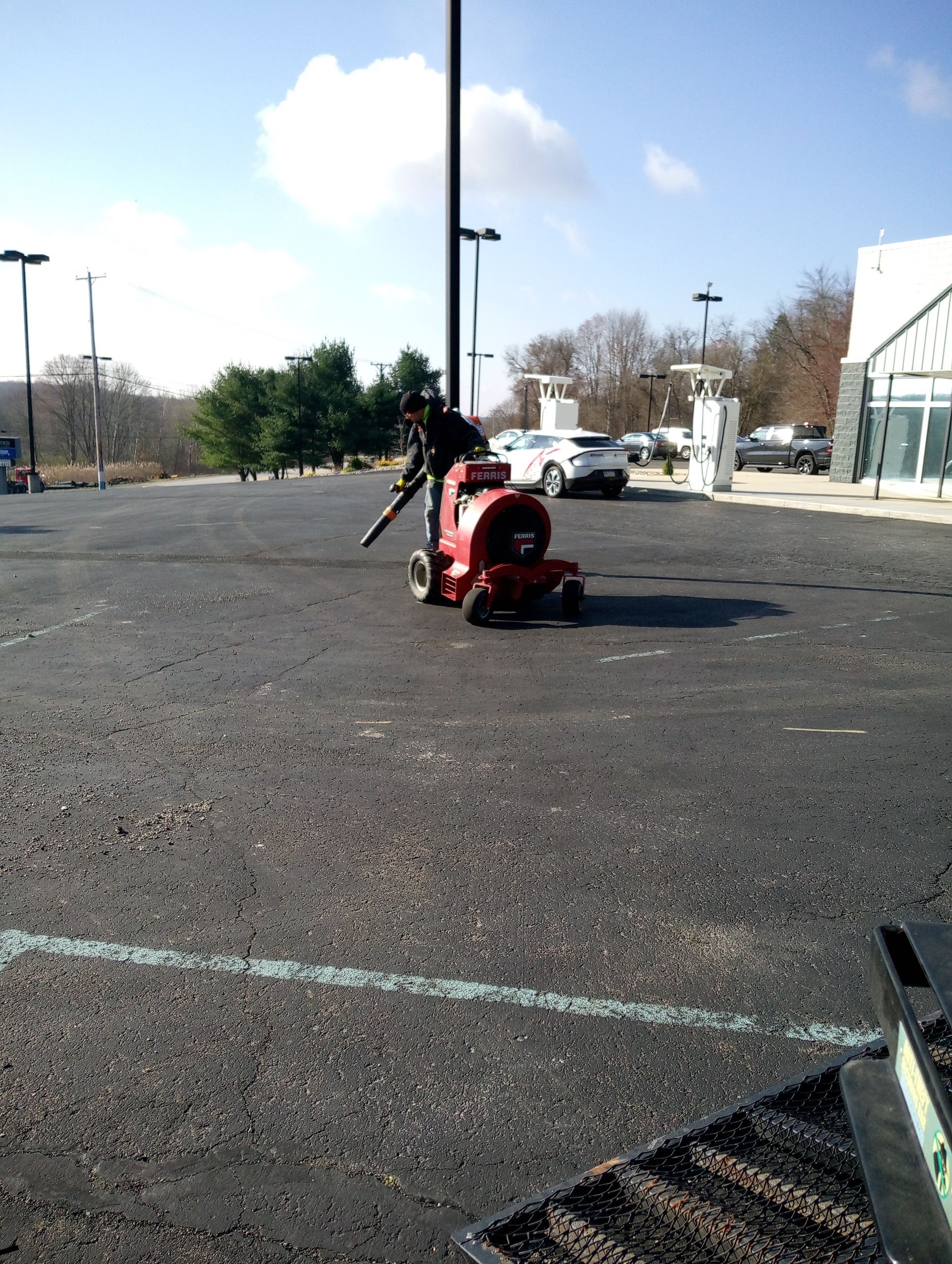 A red lawn mower is parked in a parking lot