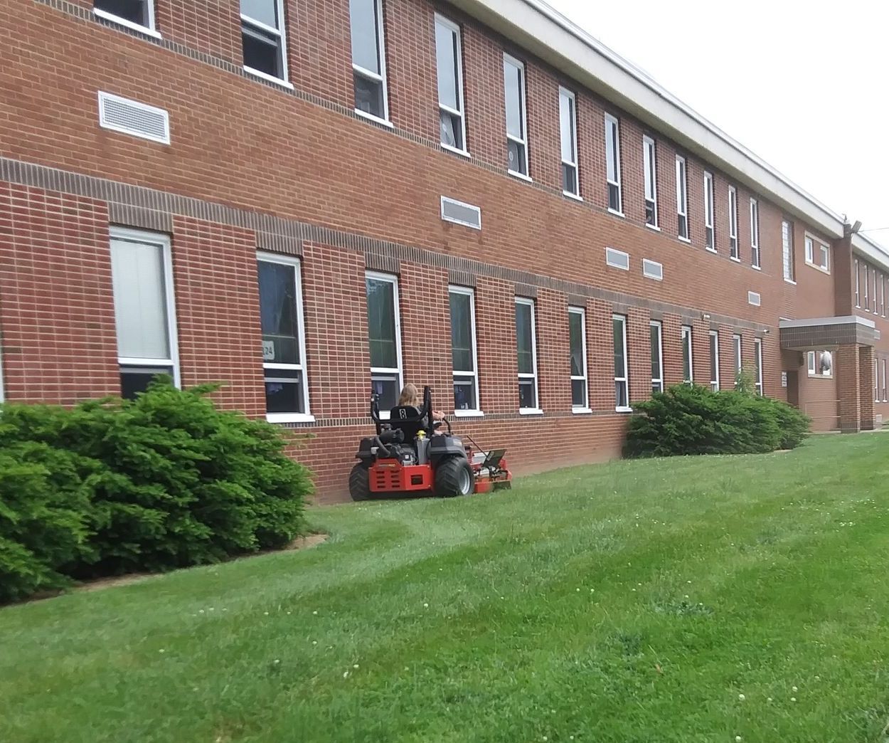 A lawn mower is parked in front of a large brick building