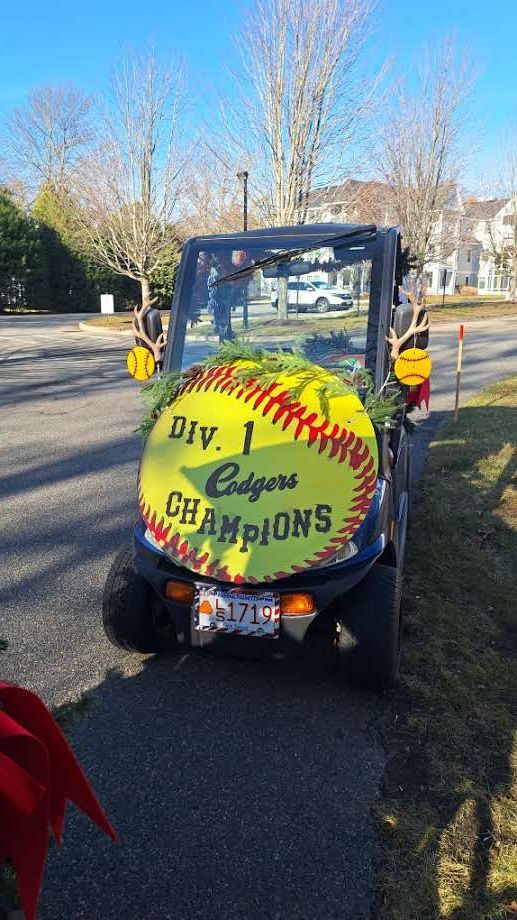 A decorated golf cart with a large softball-shaped sign reading 