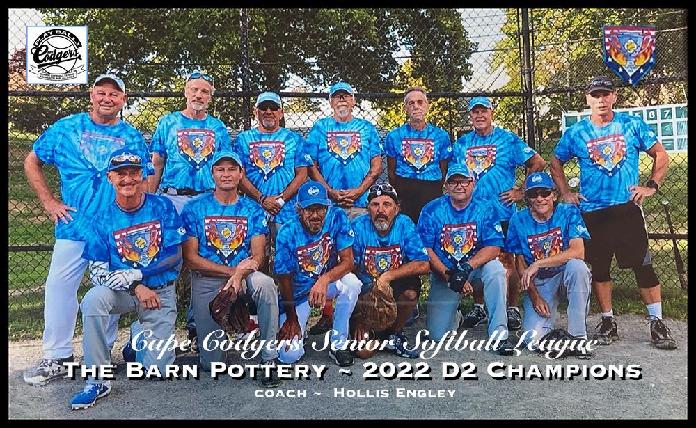 The Barn Pottery 2022 D2 Champions softball team pose for a group photo in matching blue uniforms on a field.