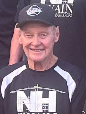 A smiling person wearing a black cap with a white logo and a black and white athletic shirt with the letters NH.