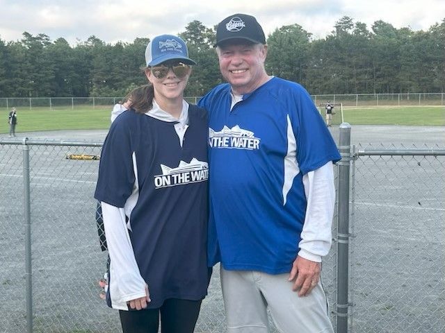 A smiling pair stand side-by-side wearing matching blue