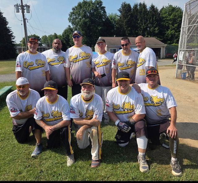 A team of eleven players in matching white and yellow baseball uniforms posing together on a grassy field.