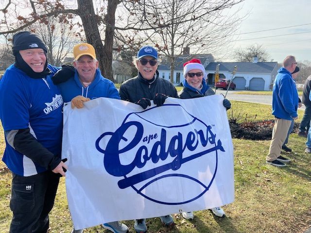Four people standing outdoors holding a white banner that says