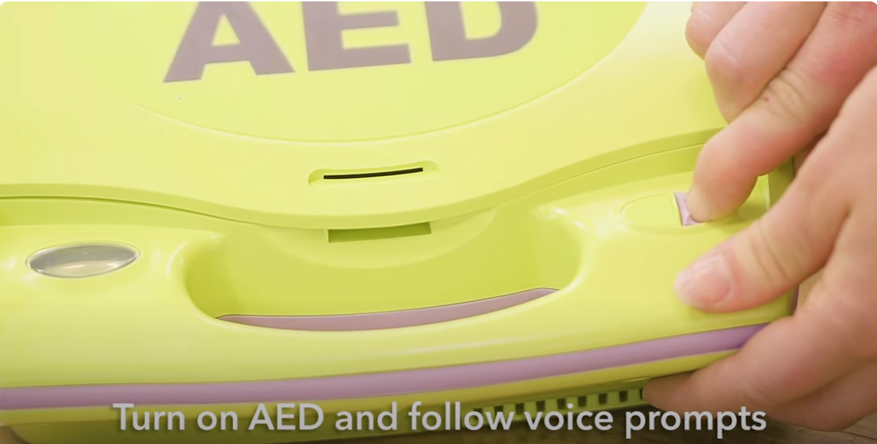 A  bright yellow AED device. The text below reads: 