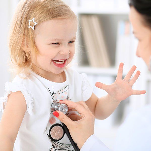 Toddler laughing as a doctor uses a stethoscope on her chest
