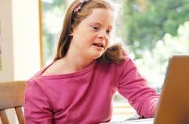 Child in a pink shirt using a laptop by a window