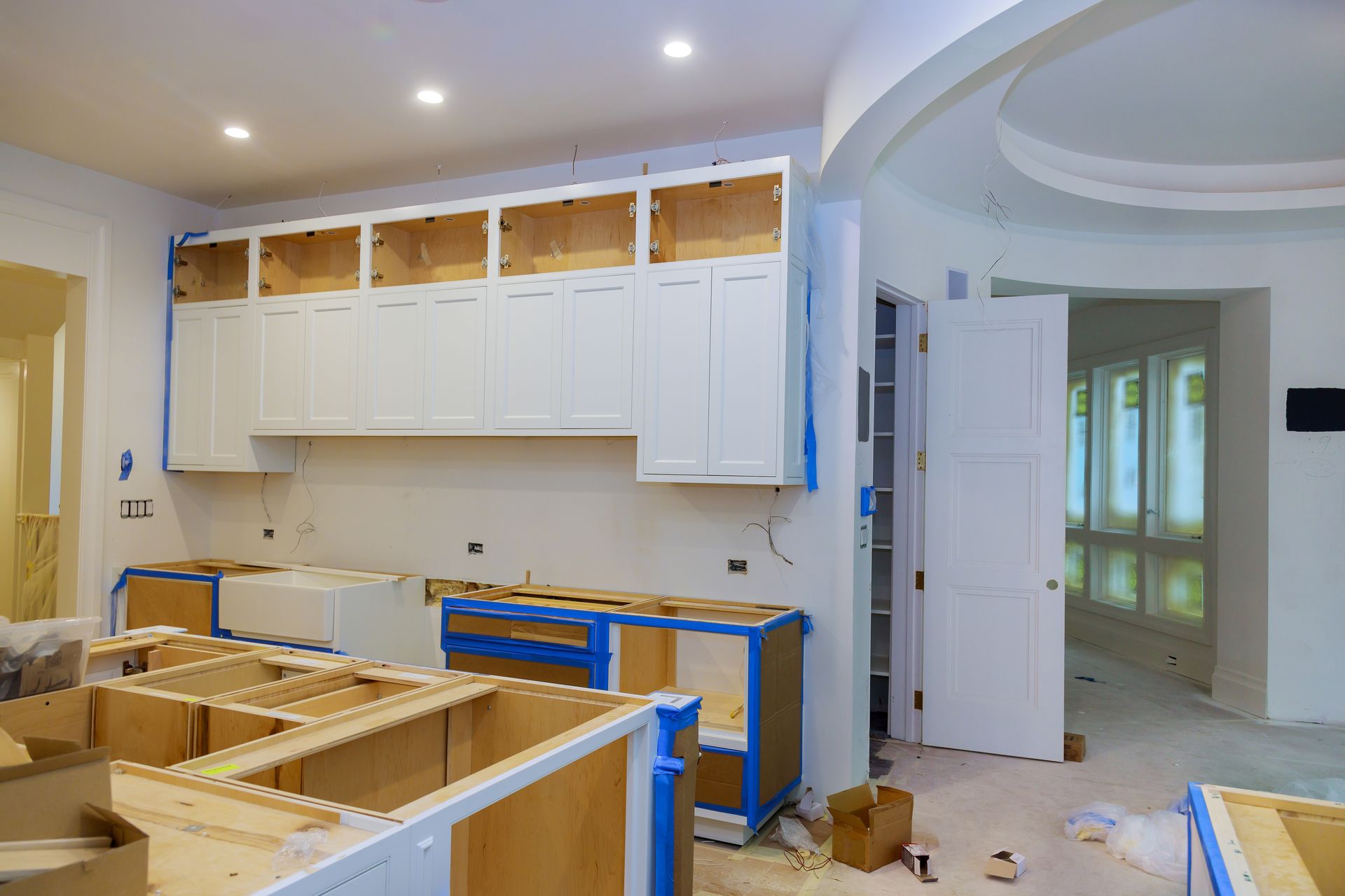 a kitchen under construction with white cabinets and wooden cabinets .