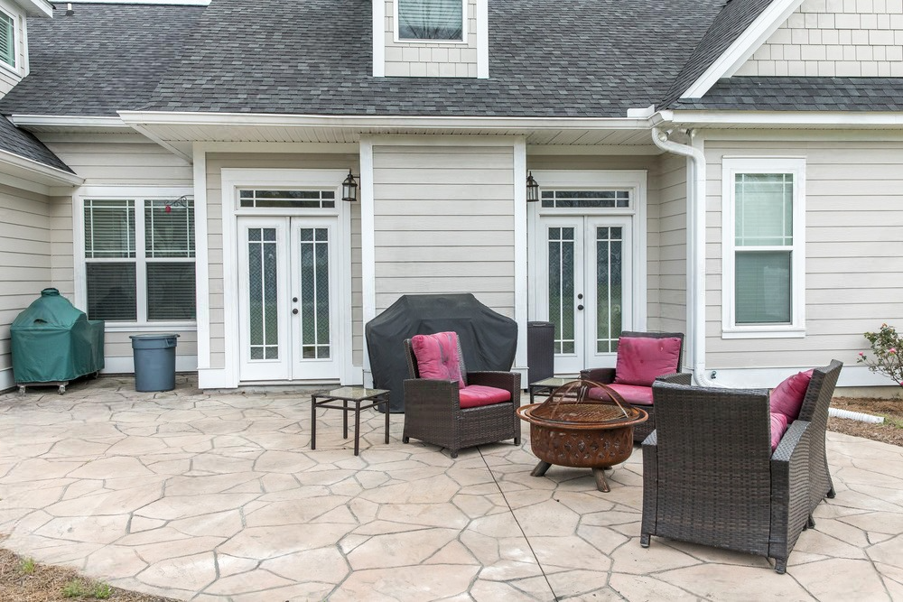 a patio with furniture and a fire pit in front of a house .