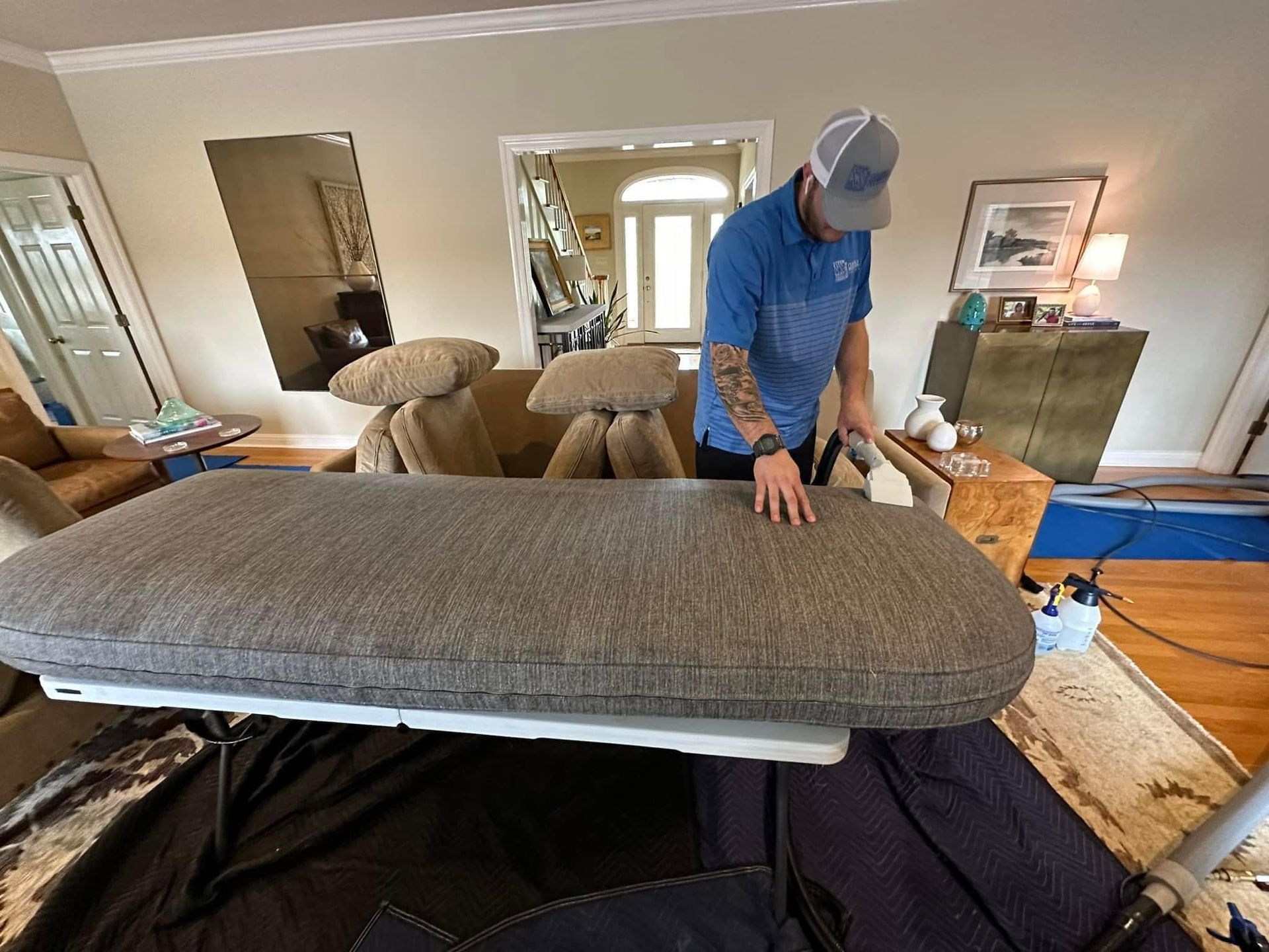 Two beige recliners in a living room being cleaned with a vacuum hose