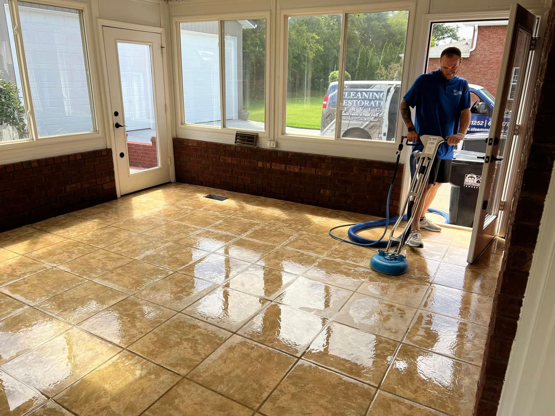 Tan tile floor with a staggered rectangular pattern beside kitchen cabinets and a dark appliance.