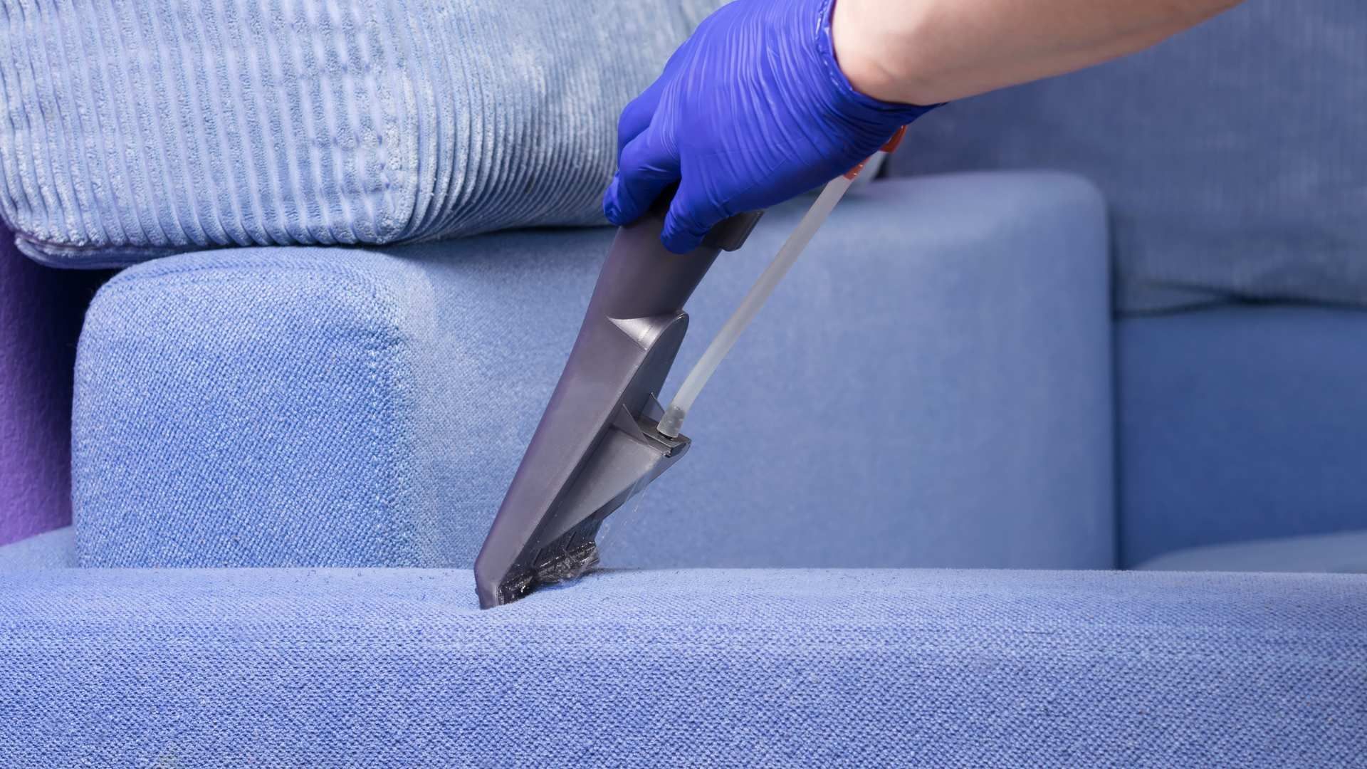 Two beige recliners in a living room being cleaned with a vacuum hose