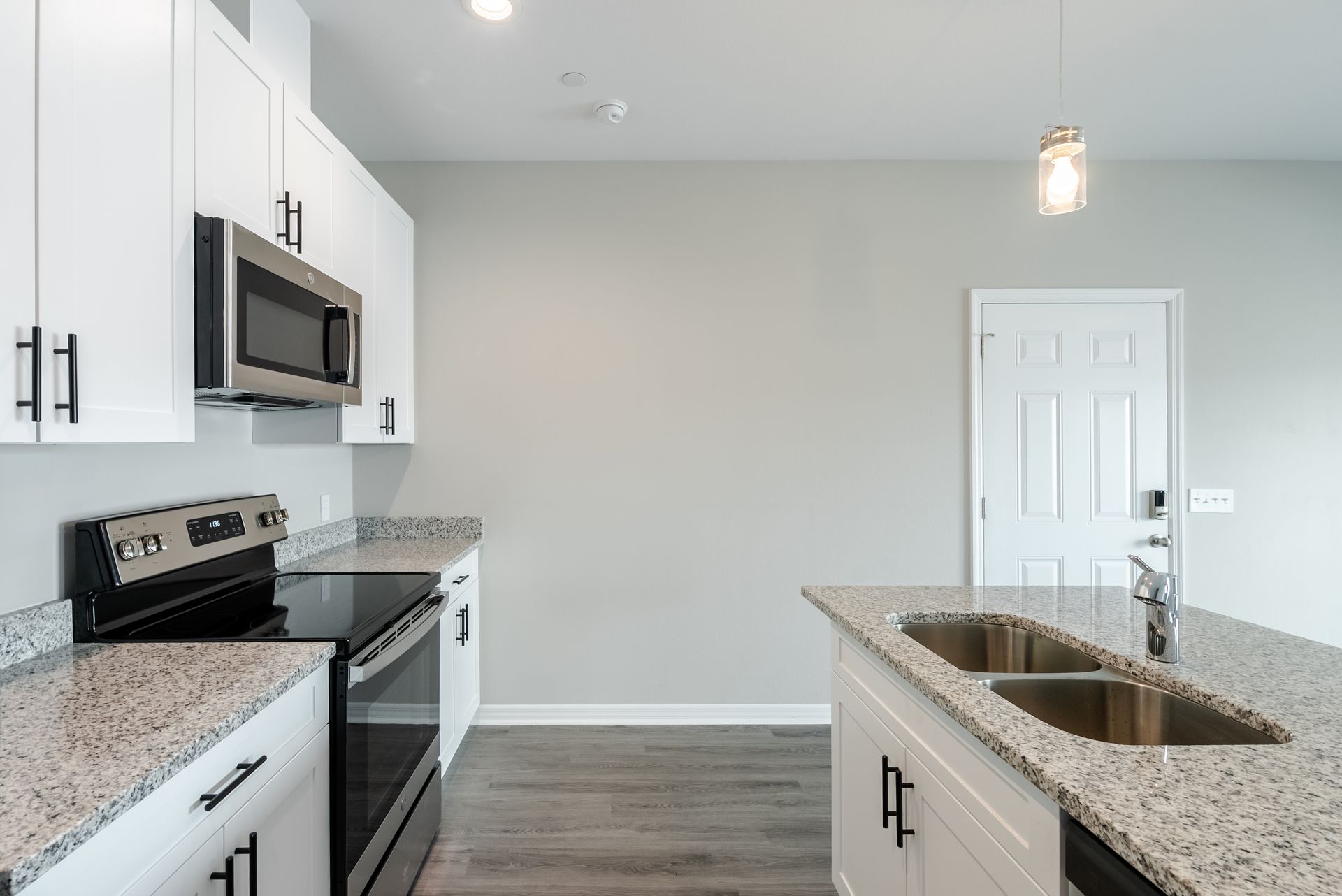 a kitchen with granite counter tops , stainless steel appliances , and white cabinets