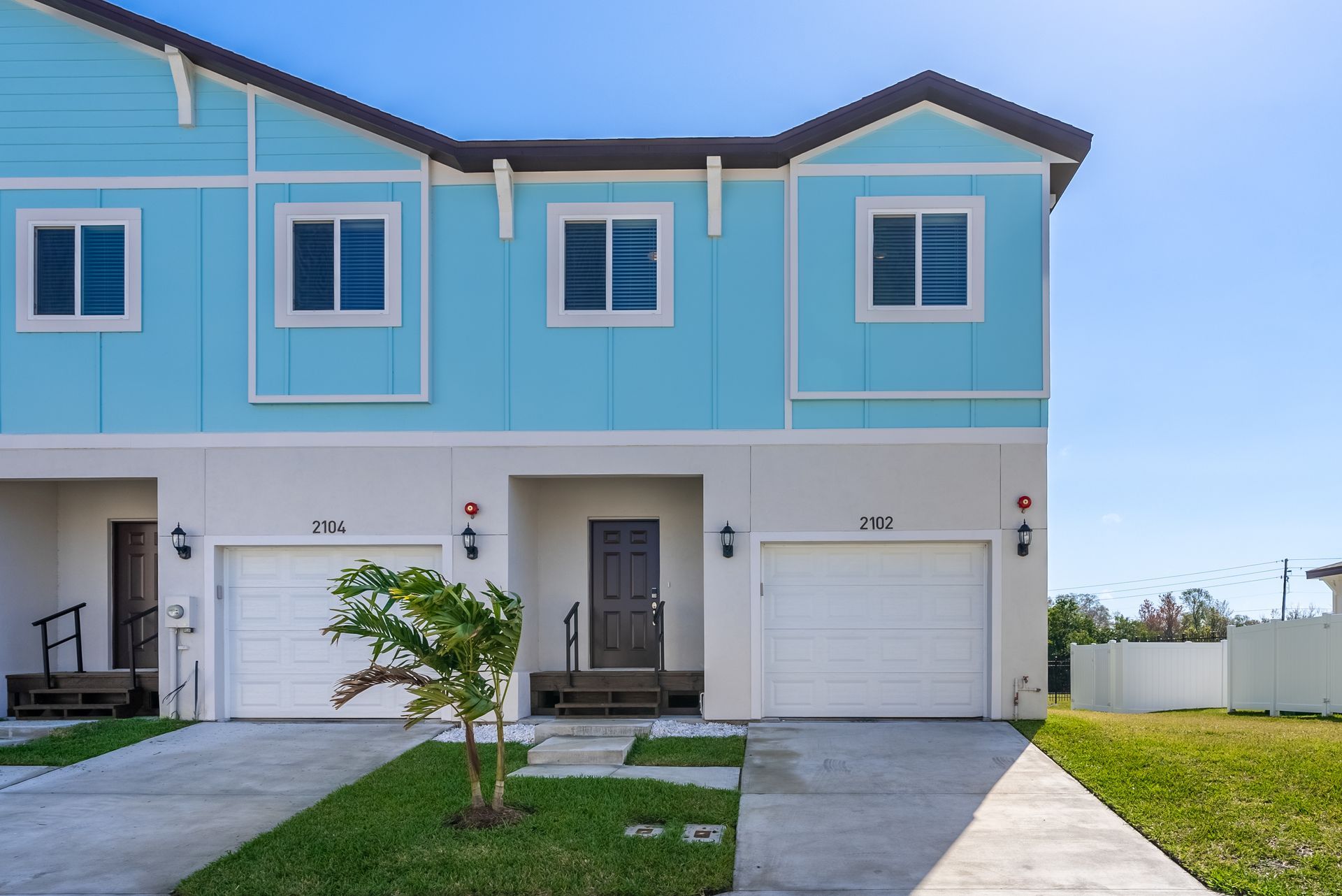 the front of a blue and white townhome with two garages .