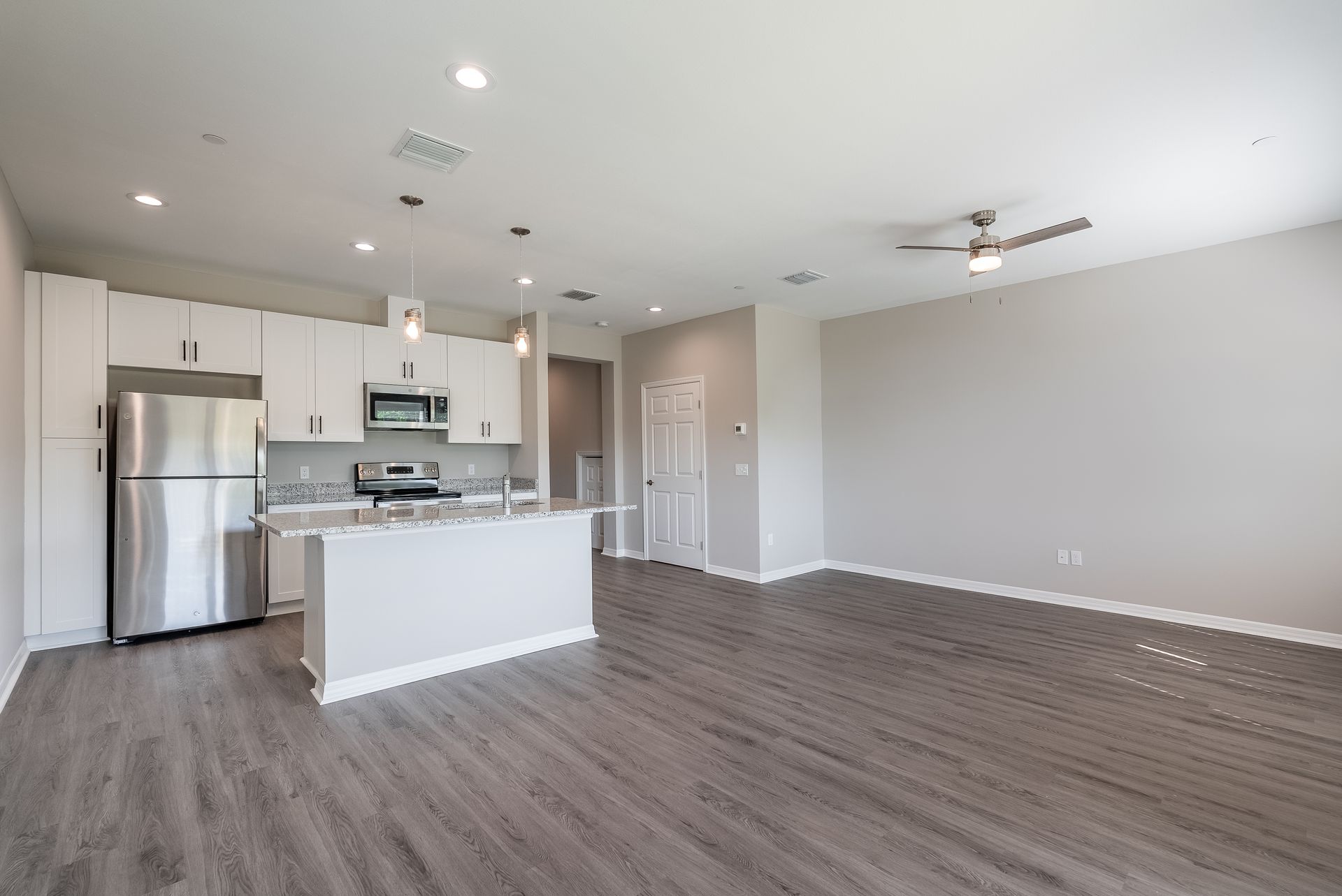 an empty kitchen with a stainless steel refrigerator and a ceiling fan