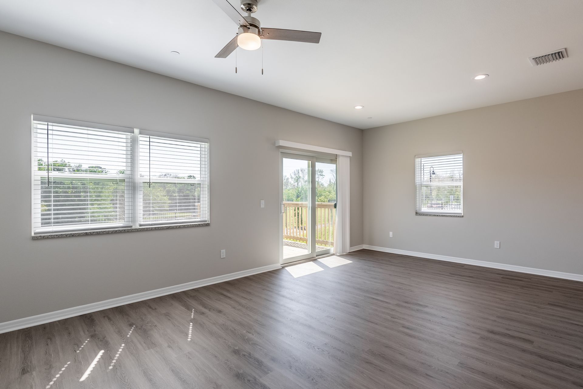 an empty living room with hardwood floors and a ceiling fan
