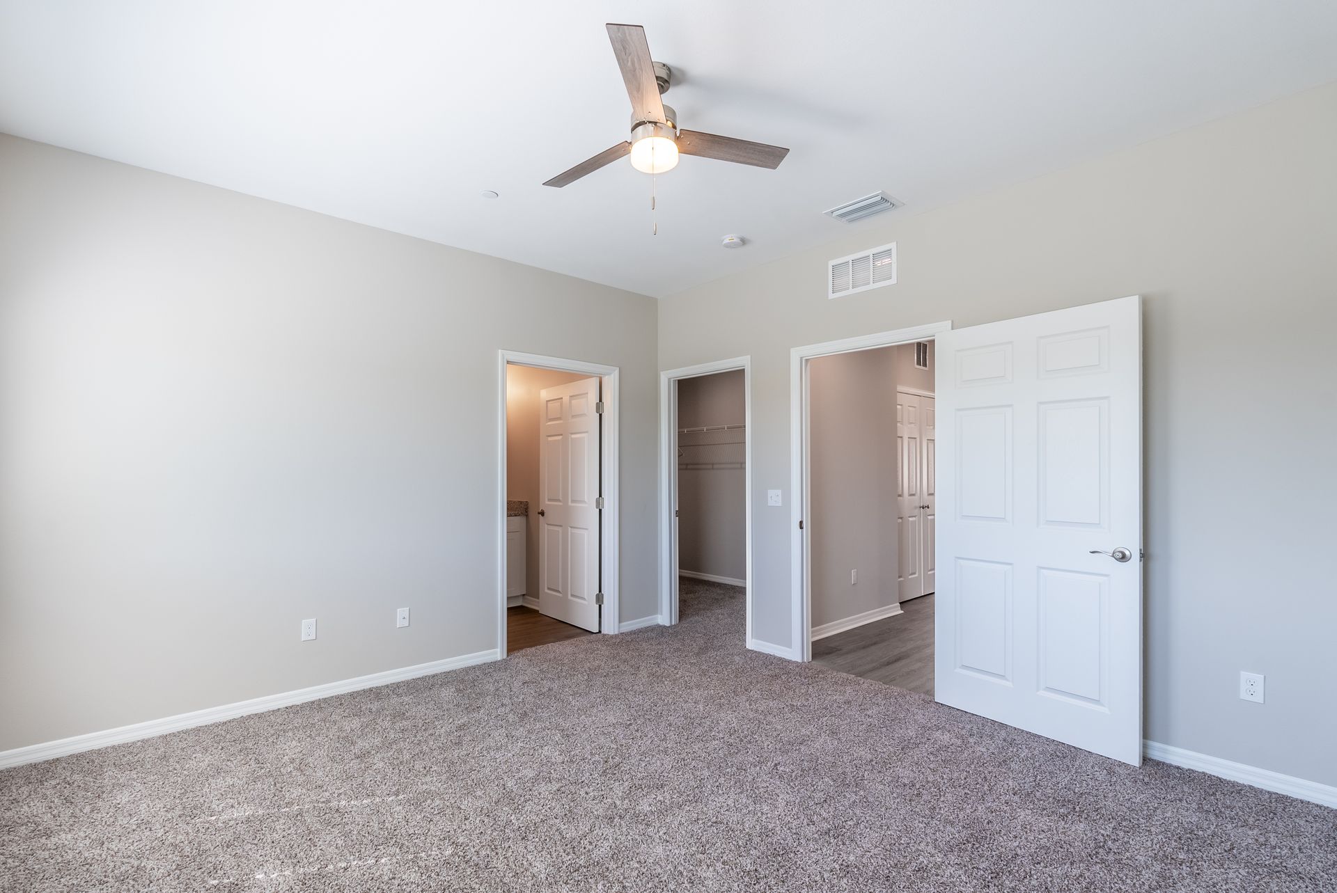 an empty bedroom with a ceiling fan and a carpeted floor .