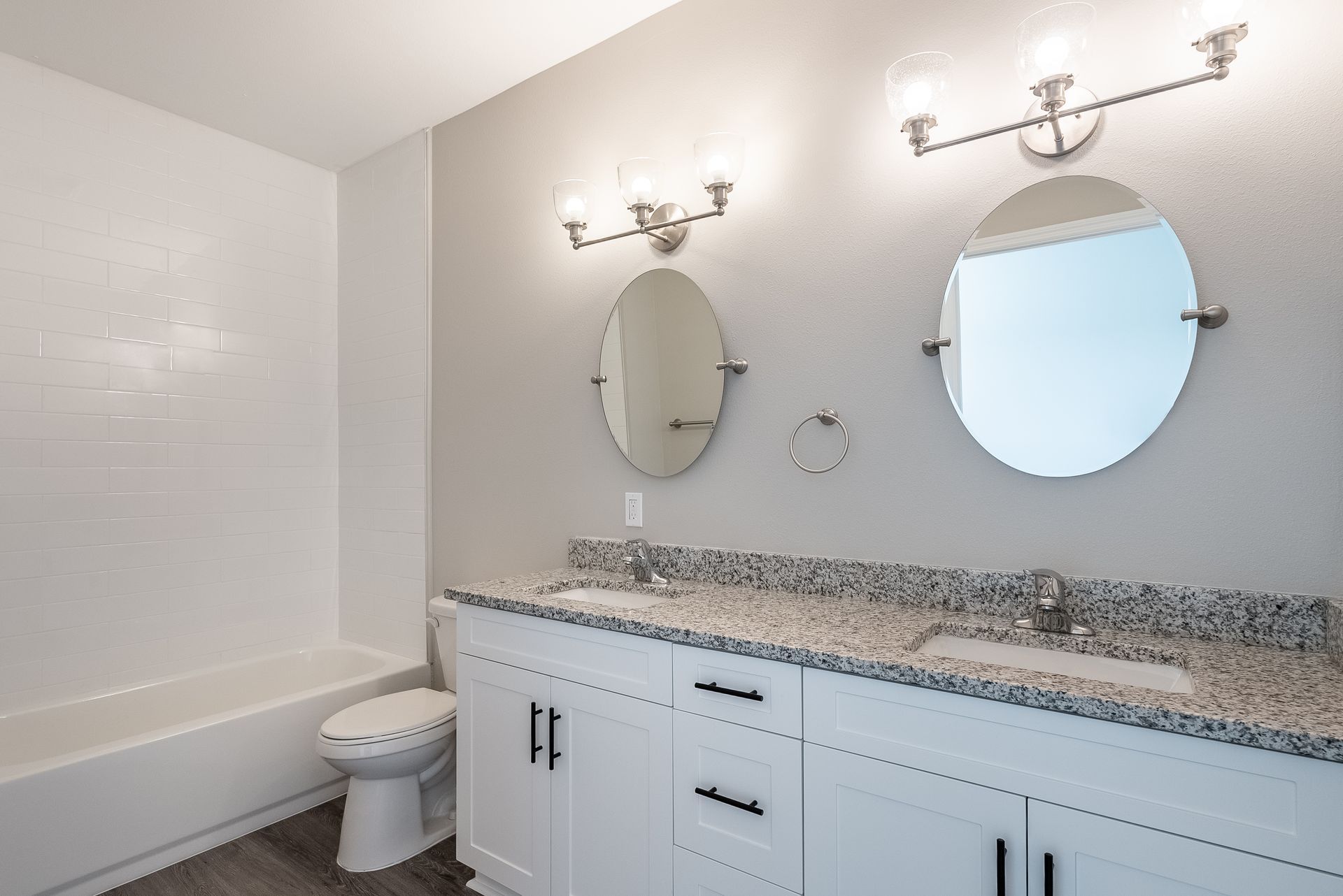 a bathroom with two sinks , a toilet , and two mirrors .