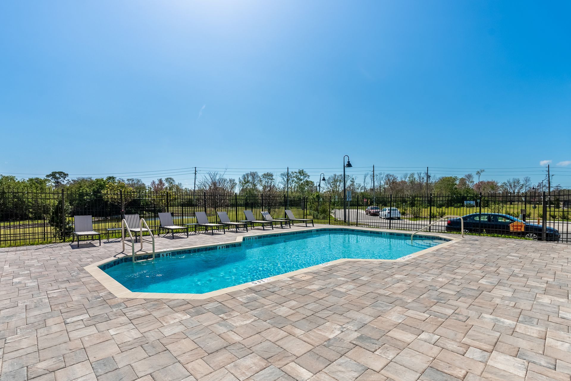 a large swimming pool surrounded by chairs and a fence at Whitney Place Townhomes